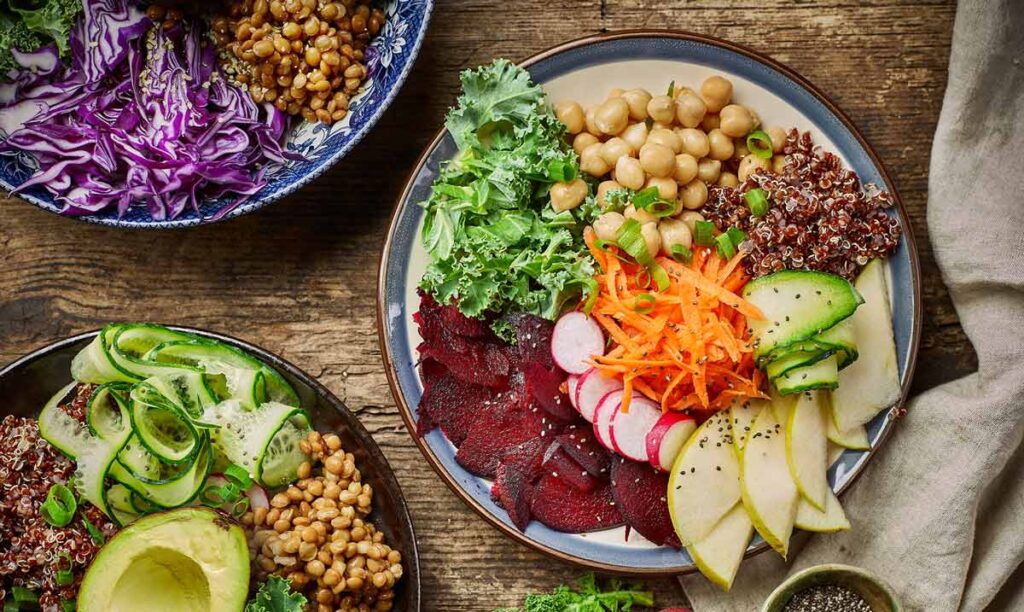 Teller mit vegetarischem und veganem Essen auf einem Tisch, reich an Gemüse, das zur Kontrolle von Blutwerten bei vegetarischer/veganer Ernährung wichtig ist.